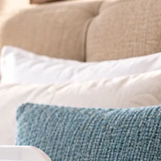 Almohadas blancas y cojín azul sobre una cama